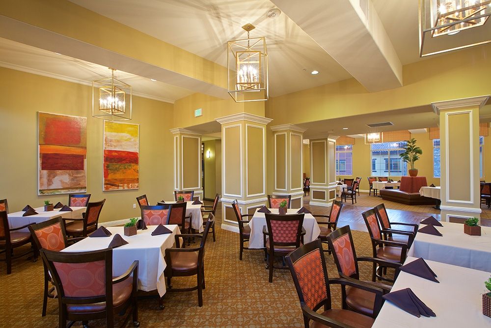 An elegant dining room with neatly arranged tables and chairs, featuring warm lighting and tasteful decor.