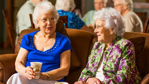 Two elderly women enjoying a friendly conversation in a community setting.