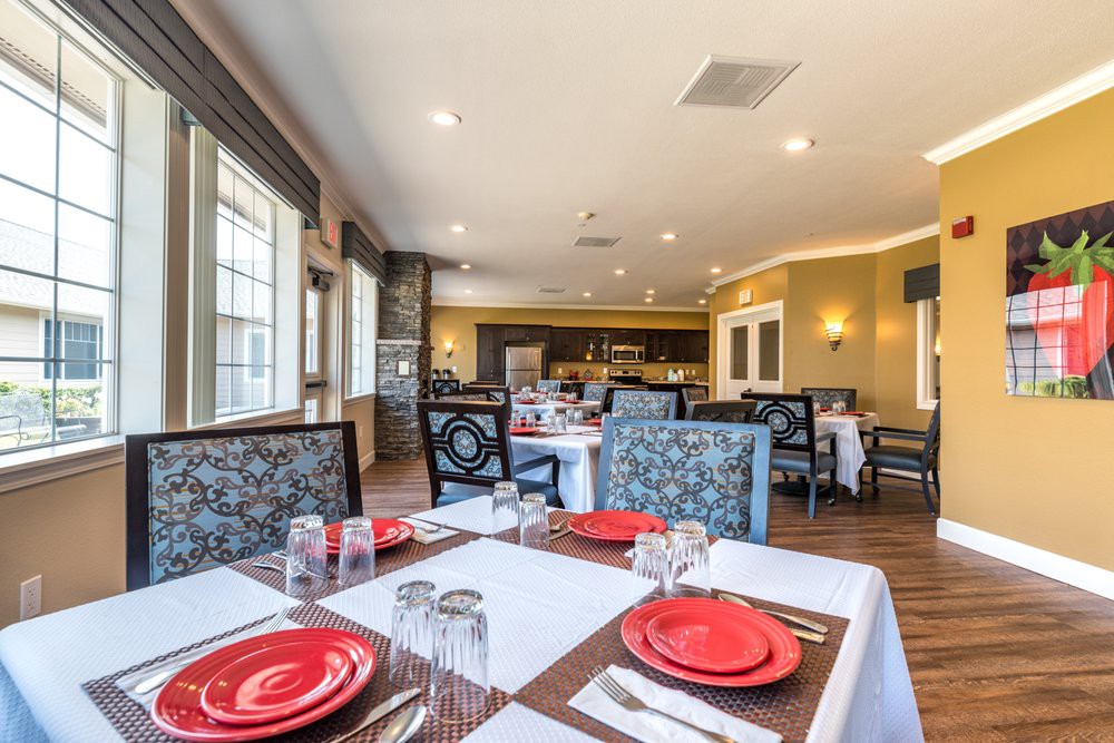 A well-decorated dining area with tables set with red plates ready for service.