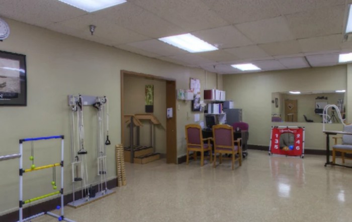 An empty waiting area in a medical facility with chairs and medical equipment.