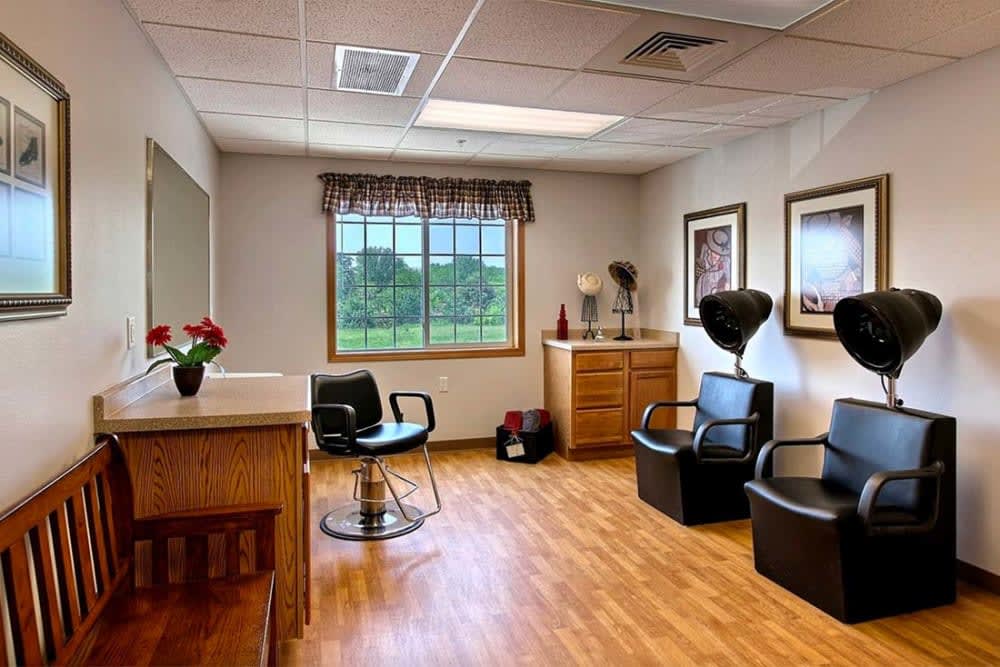 A cozy hair salon interior with chairs, mirrors, and a window overlooking greenery.
