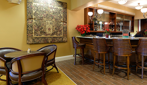 A cozy bar area featuring elegant wooden furniture, an intricate rug, and decorative accents.