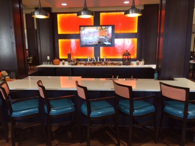 A modern bar area with blue seats and a wall-mounted television.