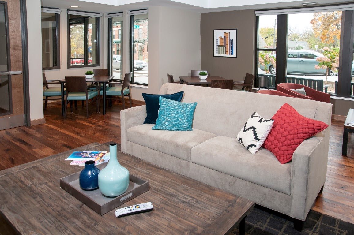 A modern living room with a beige sofa, vibrant cushions, and a wooden coffee table featuring decorative vases.