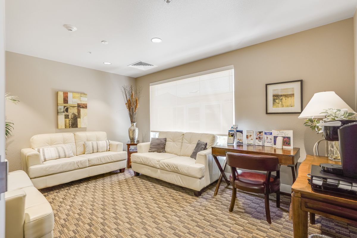 A cozy living room with white sofas, a desk, and stylish decor.