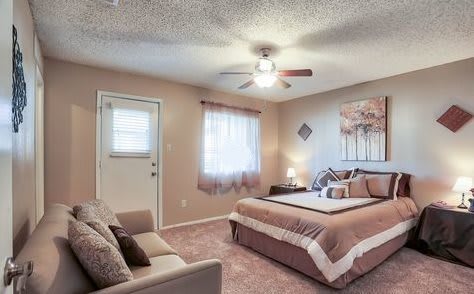 A cozy bedroom featuring a bed, ceiling fan, and soft lighting.