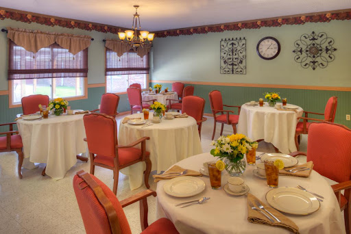 A cozy dining room featuring well-set tables with floral centerpieces, ready for a meal.
