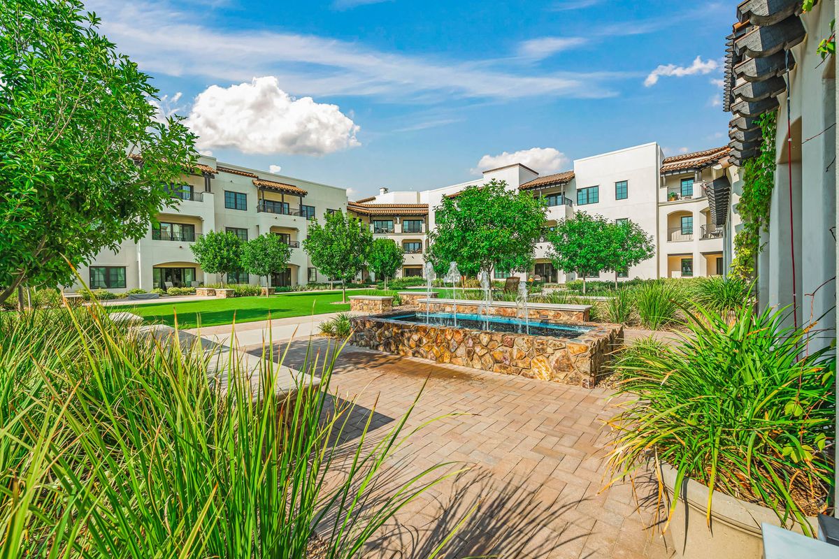 Modern apartment complex with manicured landscaping and a central fountain
