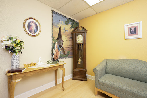 A cozy waiting room featuring a grandfather clock, wall art, and comfortable seating.