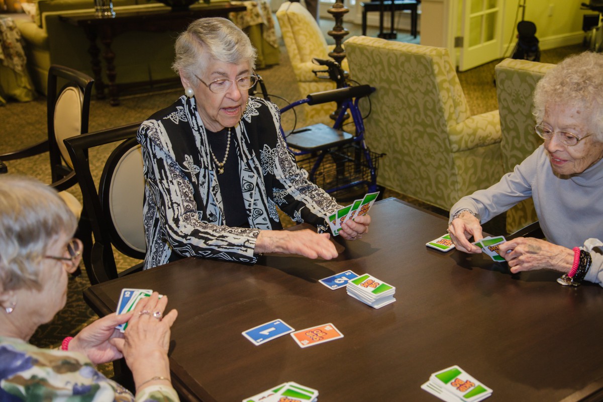 A group of elderly individuals playing a card game together indoors.