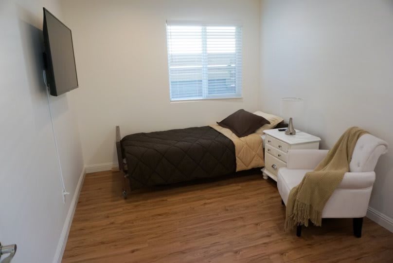 A simple, minimalist bedroom with a single bed and wooden flooring.