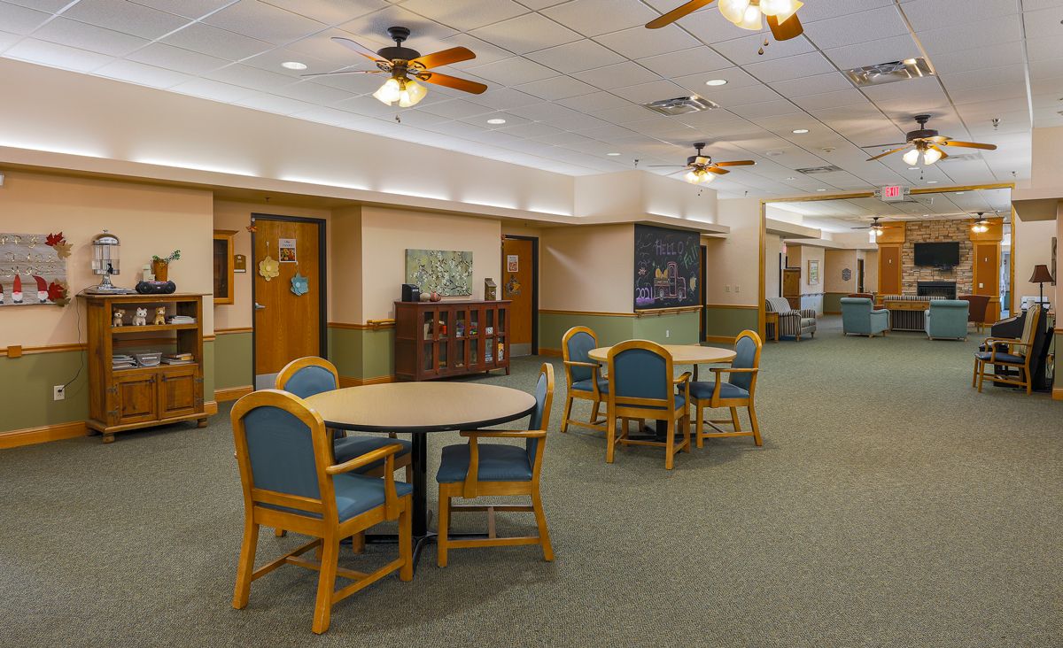 A spacious common room with tables, chairs, and ceiling fans.