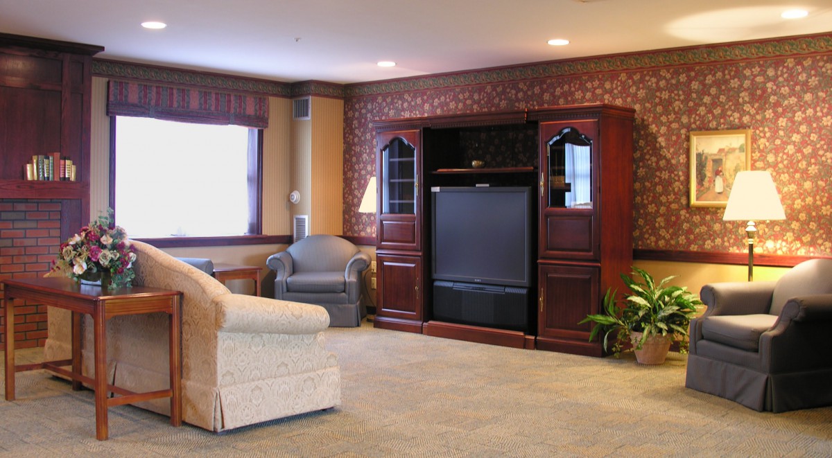 A cozy living room with comfortable seating and a large TV unit against a brick accent wall.