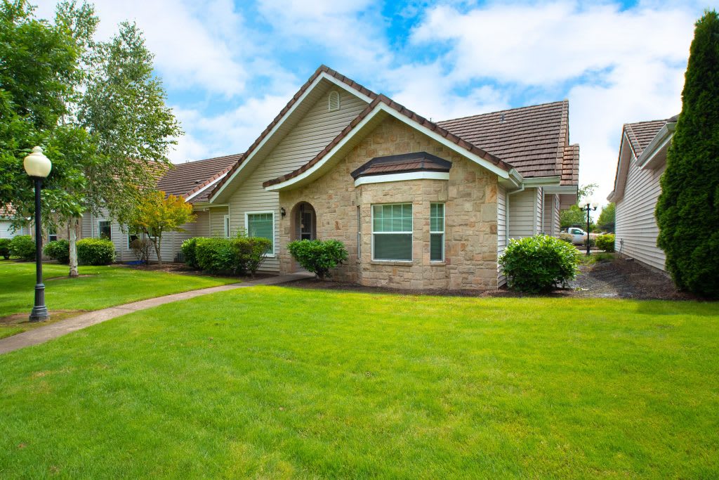 A suburban house with a well-maintained lawn and clear sky in the background.