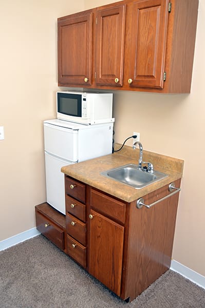 A compact kitchen setup with a sink, microwave, and refrigerator.