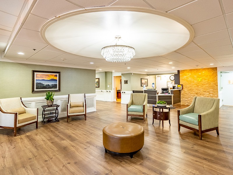 A spacious lobby area featuring comfortable seating, a central chandelier, and modern interior design.