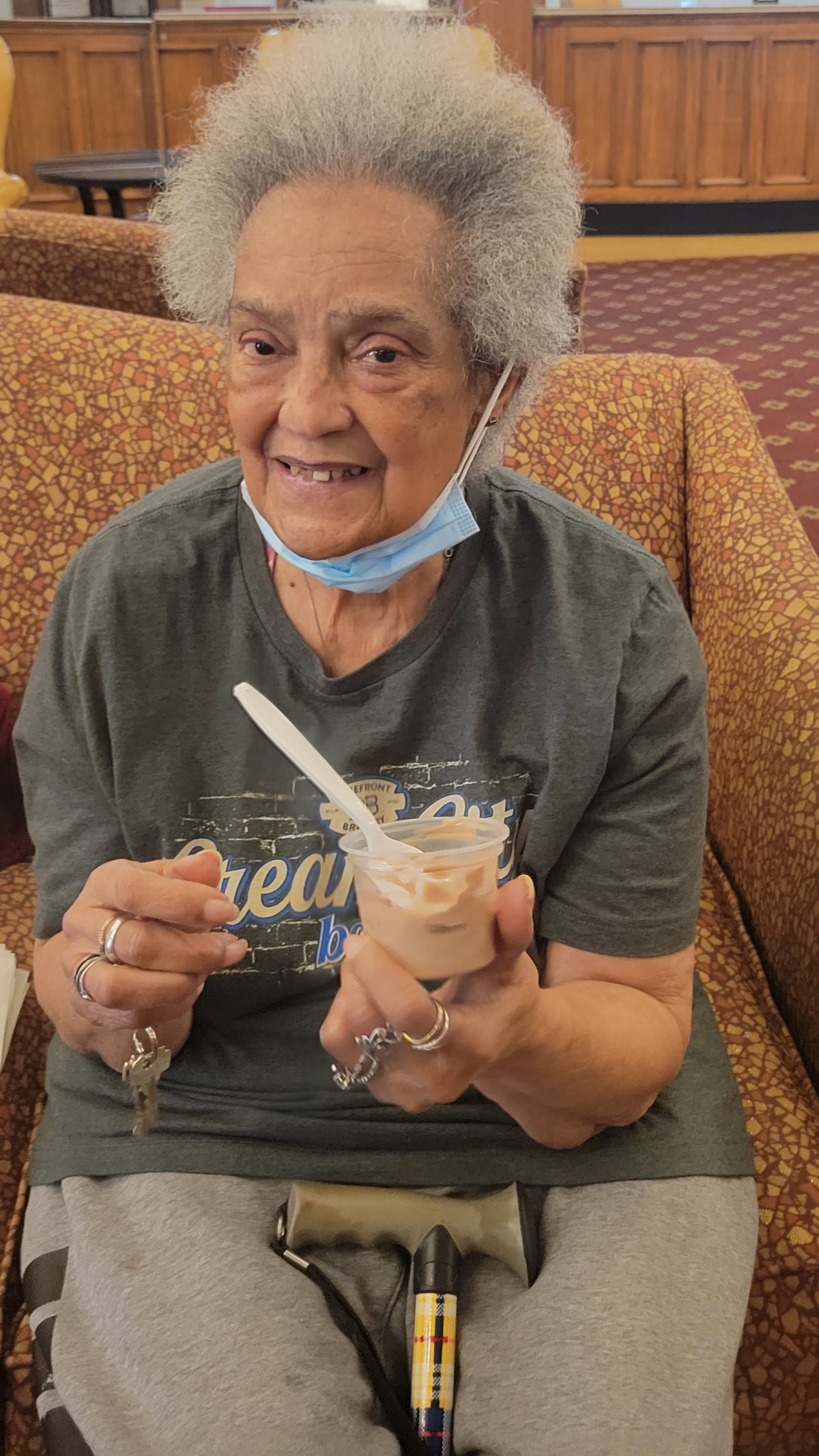 An elderly woman smiles while enjoying ice cream.