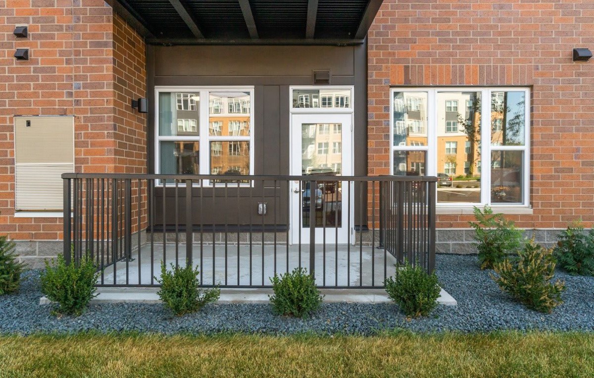 A modern apartment patio with a small fence and potted plants.