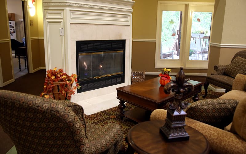 A cozy living room with a fireplace, armchairs, and a decorated coffee table.