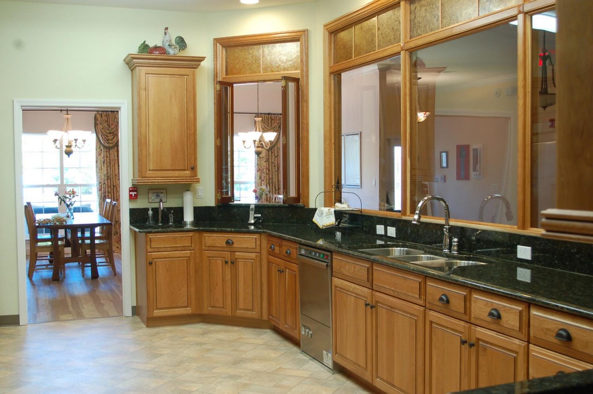 A spacious kitchen featuring wooden cabinets and a dark countertop with a double sink.