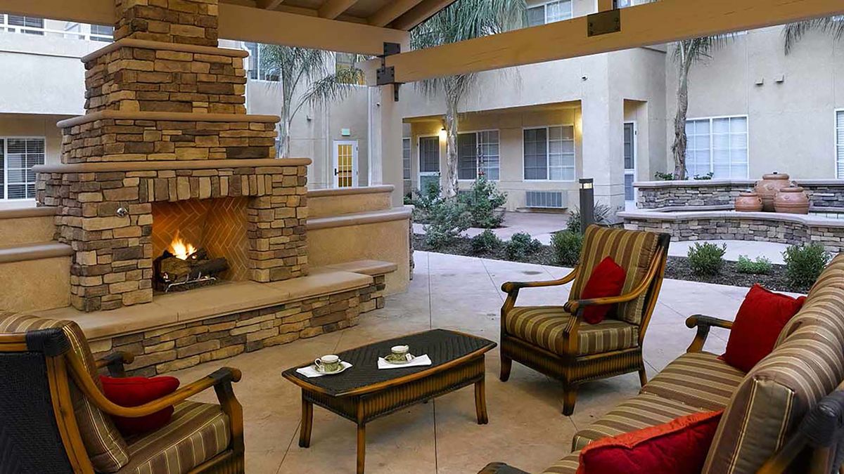 A cozy outdoor patio with comfortable seating and a fireplace in a courtyard setting.