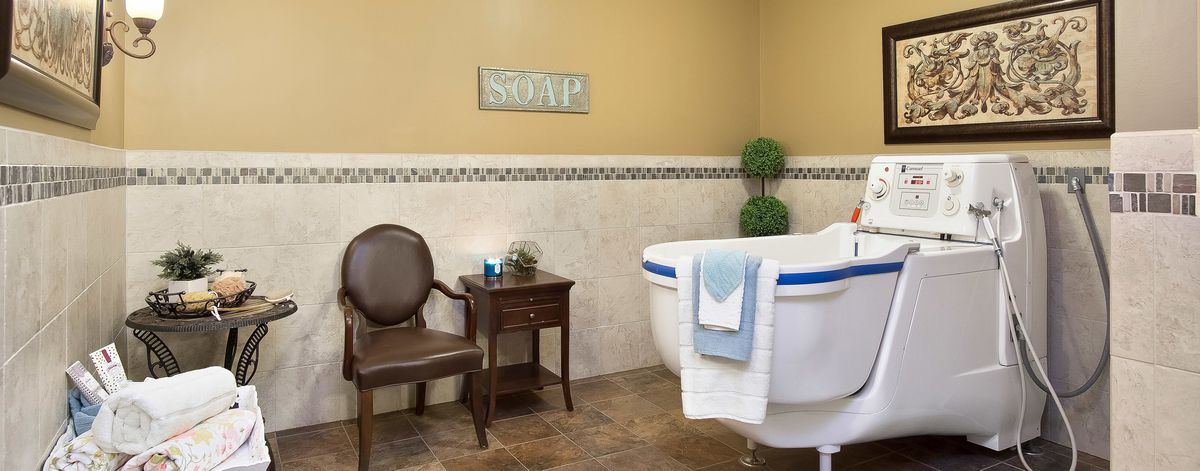 A cozy bathroom with a classic bathtub, elegant chair, and side table.