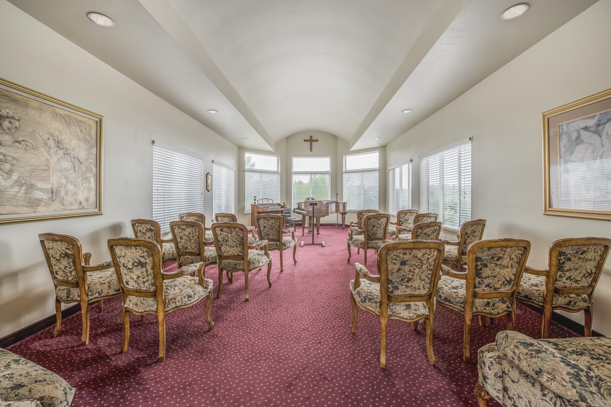 A small chapel interior with lined chairs and large windows.