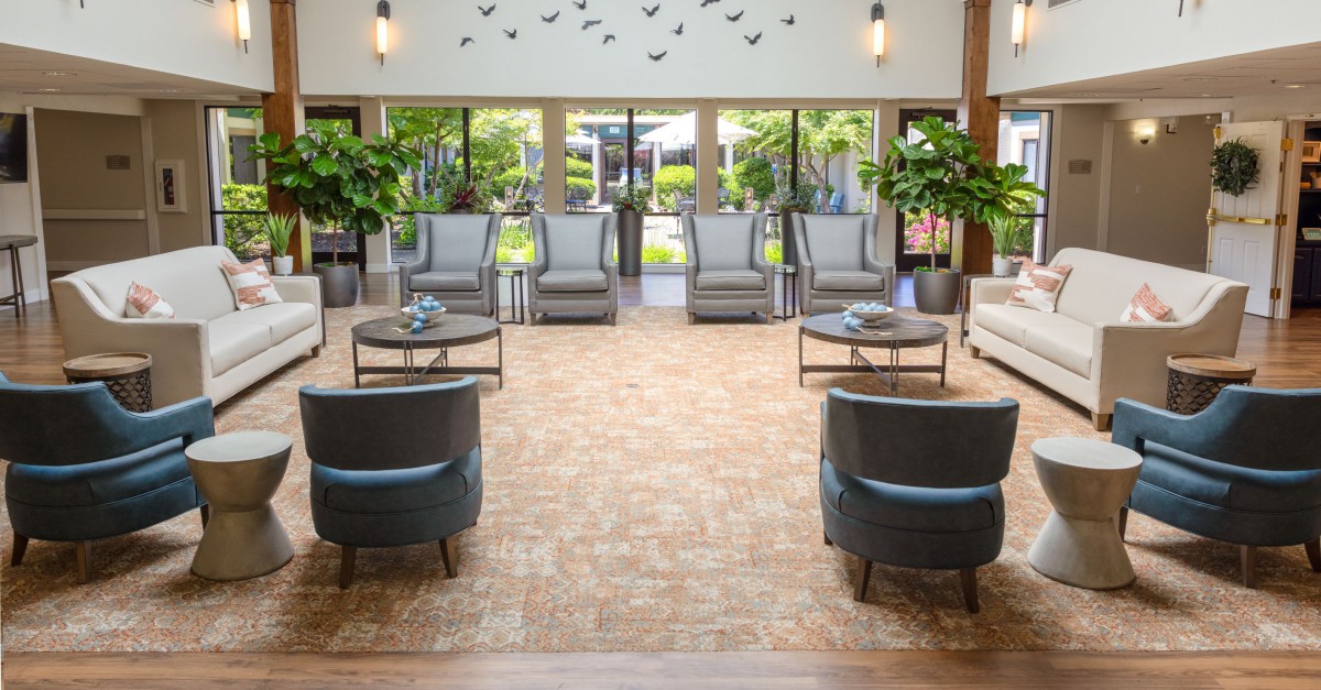 A spacious lobby with elegant seating, large windows, and lush plants.