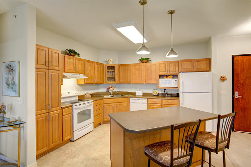 A spacious and well-lit kitchen featuring wooden cabinetry, modern appliances, and a central island.
