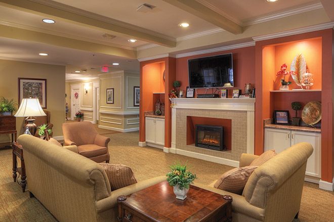 A cozy living room featuring a fireplace and seating area, decorated with warm tones and stylish furnishings.