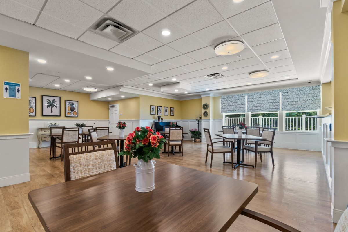 A modern dining area with tables, chairs, and a vase of flowers on a wooden table.