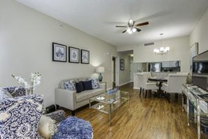 A modern living room with hardwood floors, a comfortable sofa, and an open layout leading to the dining area.