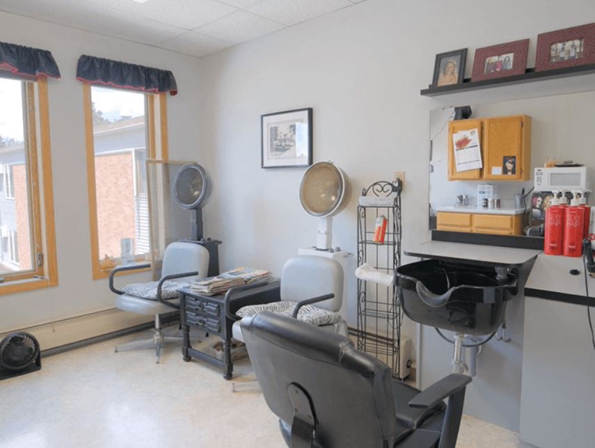 A cozy hair salon with seating, hair dryers, and a mirror station.