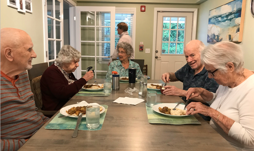 A group of seniors enjoying a meal together at the dinner table.