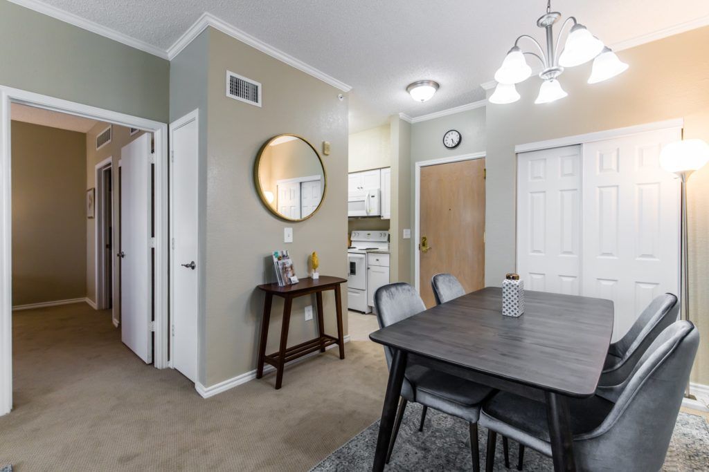 A modern dining room with a dark wooden table, upholstered chairs, and a round wall mirror.