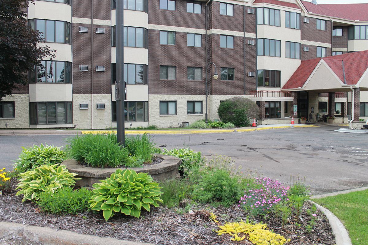 An urban landscape featuring a multi-story building with surrounding greenery and a small garden area.