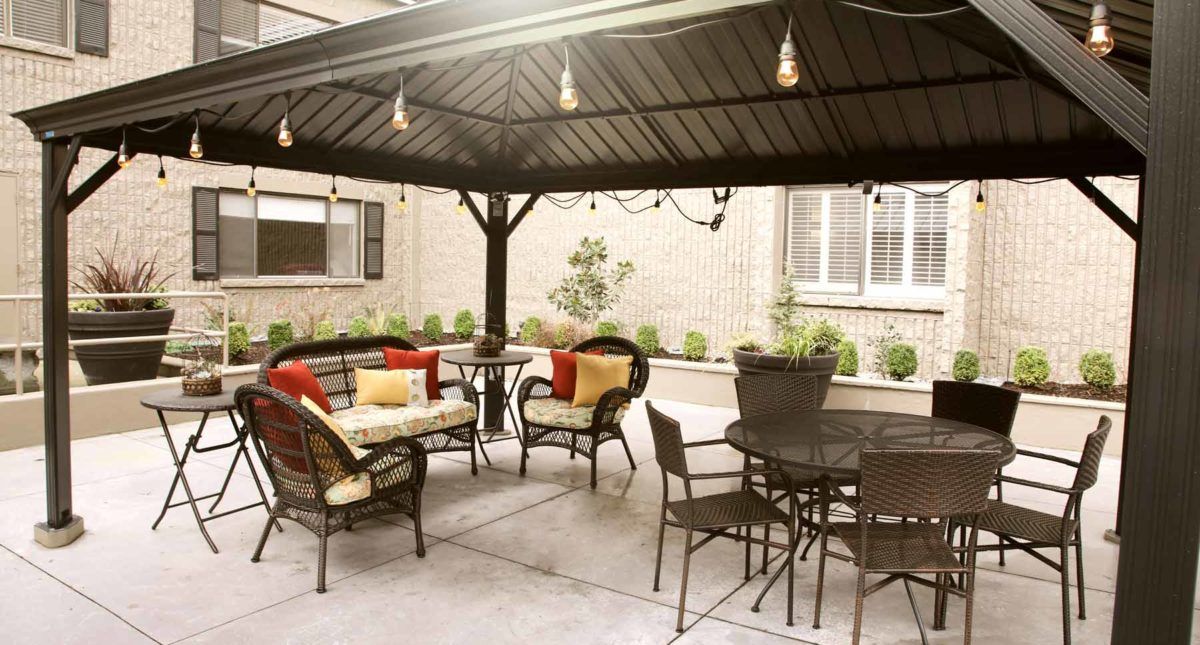 A cozy outdoor patio with a gazebo, featuring comfortable seating and ambient lighting.
