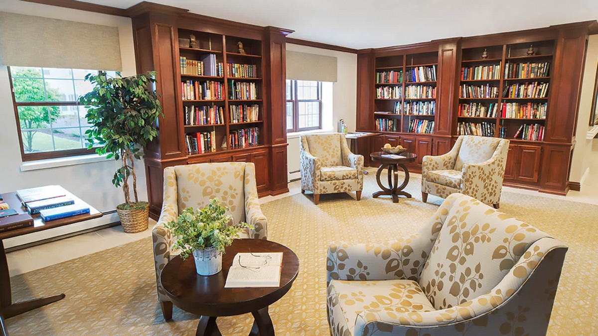 A cozy library space with bookshelves, armchairs, and a small table.