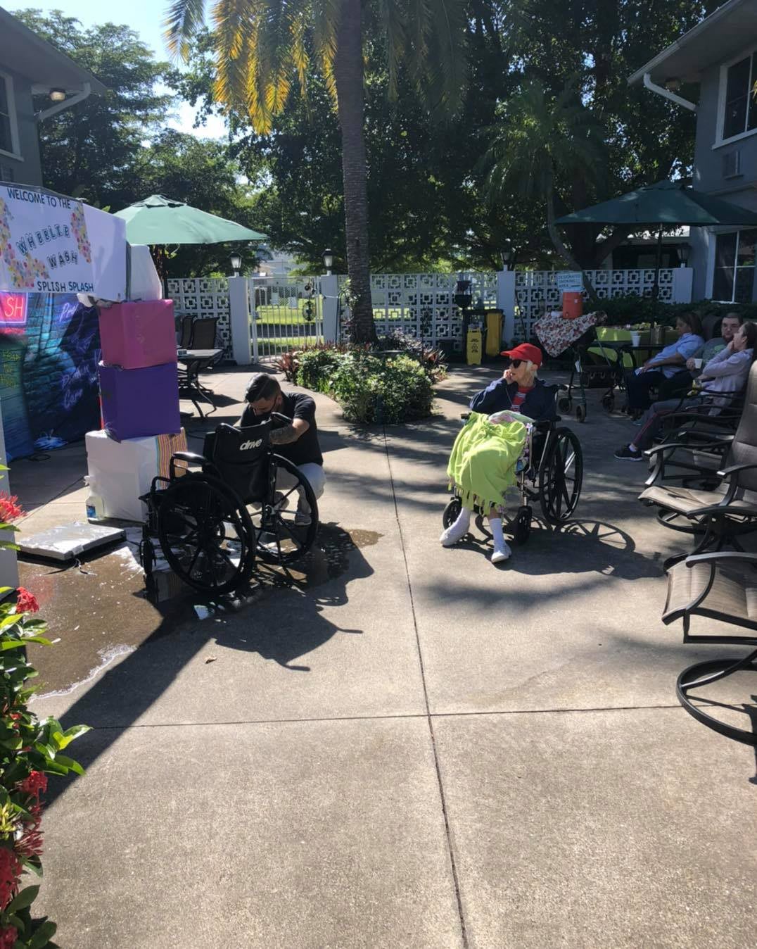 People enjoying a sunny day outside in wheelchairs under garden umbrellas.