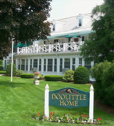 A charming home with a lush garden and a sign reading 'Doolittle Home'.