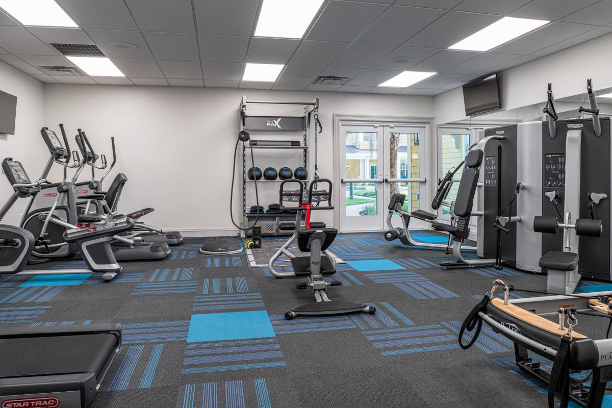 A modern gym facility with a variety of exercise equipment and workout machines.