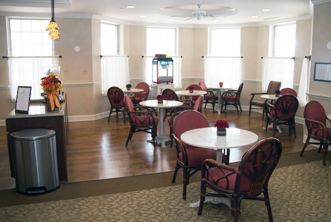 A cozy cafe interior with multiple tables and chairs, surrounded by large windows.