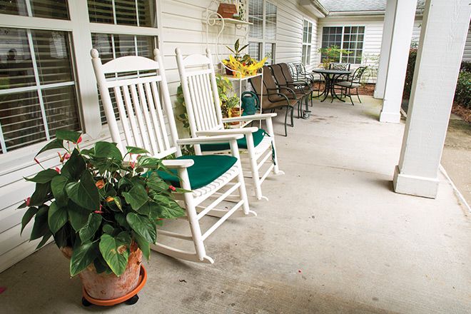A peaceful porch with white rocking chairs and potted plants, perfect for relaxation.