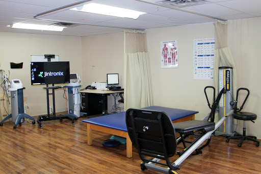 A well-equipped physical therapy clinic with treatment tables and exercise machinery.