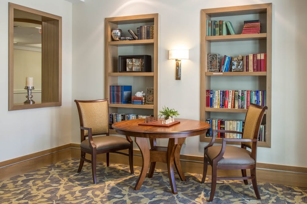 A cozy reading area featuring two bookshelves, a small wooden table, and chairs.