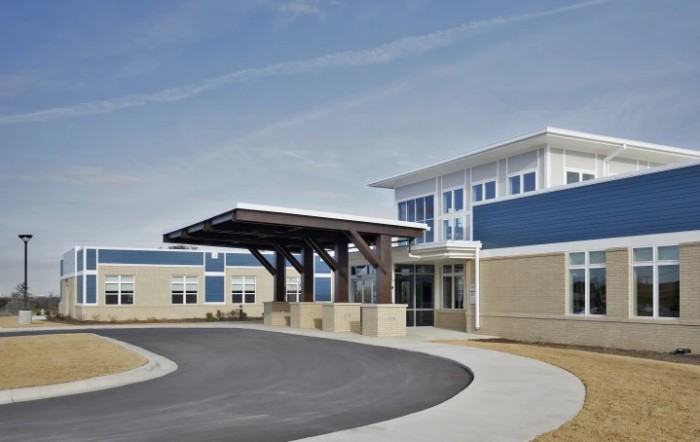 A modern building with a covered entrance and curved driveway.