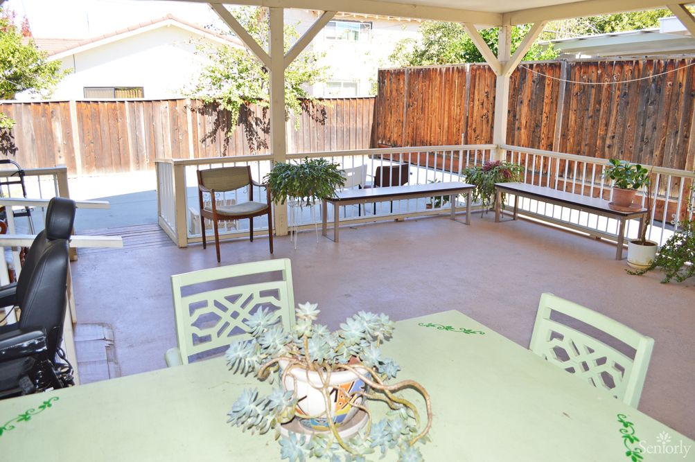 A cozy outdoor patio with seating and plants under a gazebo.