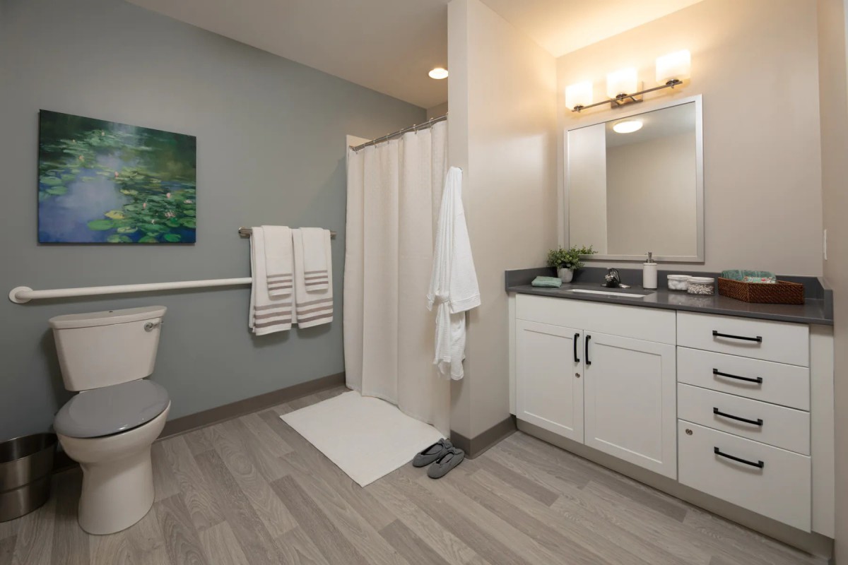 A modern bathroom featuring a sleek shower area, large mirror, and ample cabinetry.