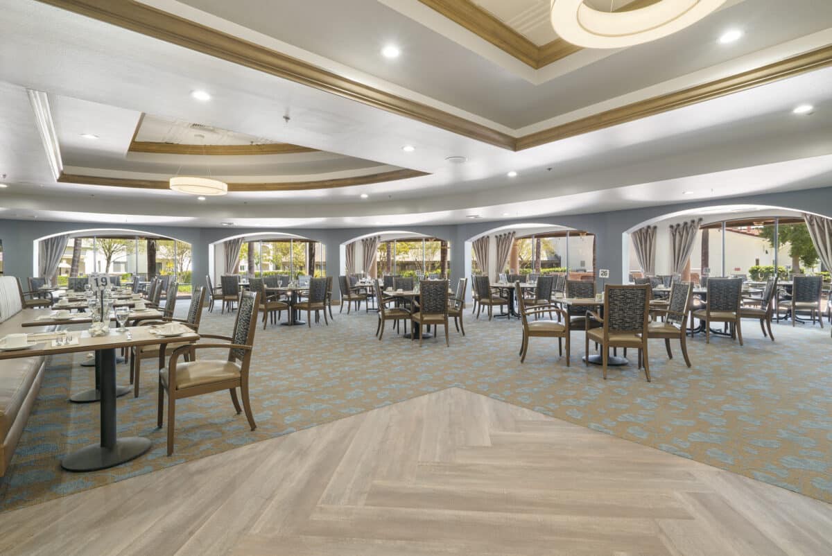 A modern dining hall with neatly arranged tables and chairs, featuring elegant interior design and ambient lighting.