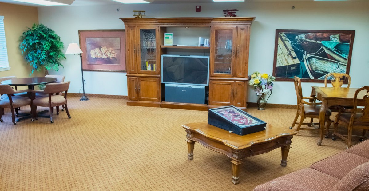 A cozy living room with a large wooden cabinet housing a television, and a coffee table in the center.